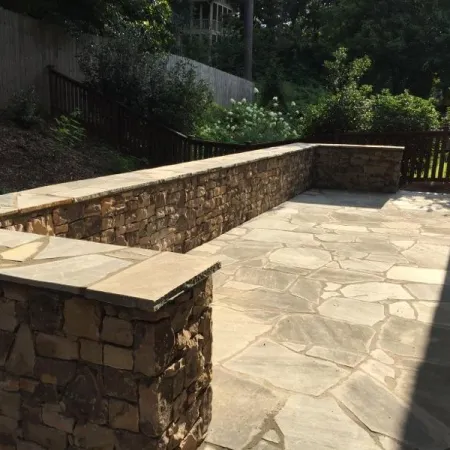 Natural stone patio with retaining wall creating a functional side-yard space