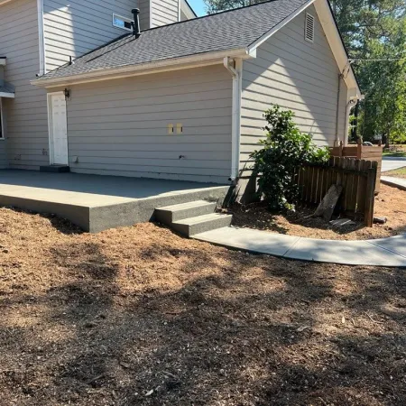 Newly poured concrete steps and walkway beside a house with a landscaped yard.
