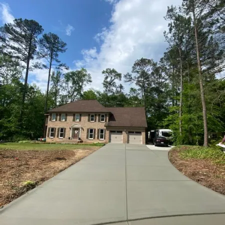 a house with a driveway and trees around it