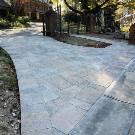 a stone walkway with a fence and trees on the side