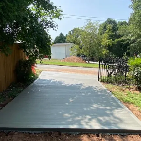 a driveway with a fence and trees