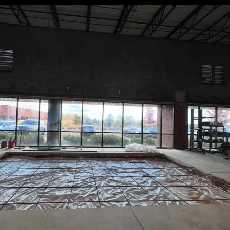 Construction site inside a building with plastic sheeting and metal rebar laid out for concrete floor work.