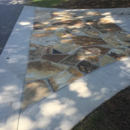 a stone walkway with grass and trees
