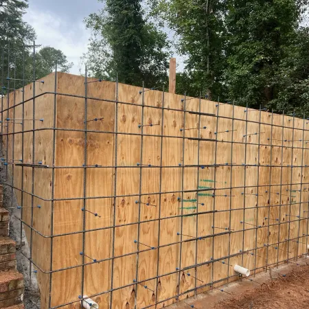 a fenced off area with a brick wall and trees in the background