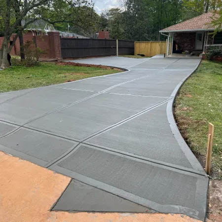 a driveway with a fence and grass