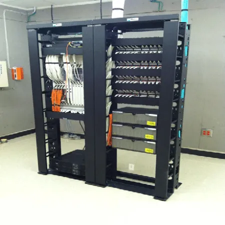 Black server rack with organized network cables and equipment in a clean server room with gray walls.