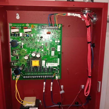 Open red metal panel revealing a green electronic circuit board with capacitors, wires, and connectors inside.