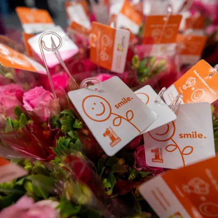 Bouquets of pink flowers with orange and white tags featuring smiley faces and the word smile.