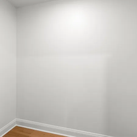 Empty white room corner with wooden floor and baseboard molding under soft lighting.