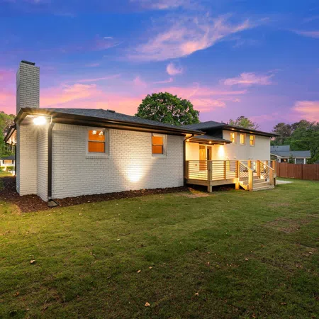 Modern white brick house with large backyard at sunset and a vibrant purple and blue sky.