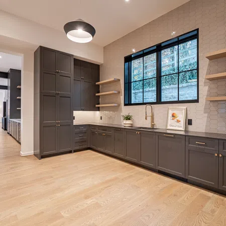 Modern kitchen with dark cabinetry, hexagonal tile backsplash, large window, and light wood flooring.