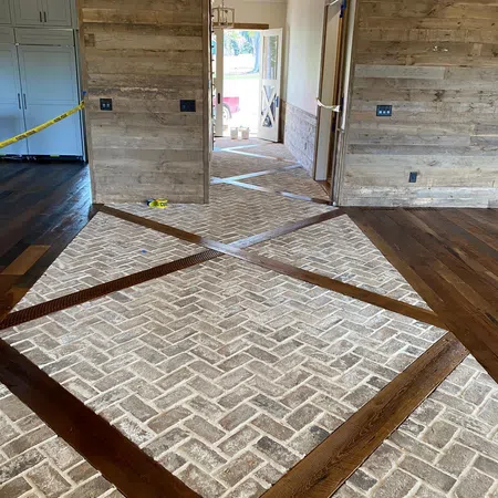 Rustic interior hallway with textured stone tile floor and dark wood accents under renovation.