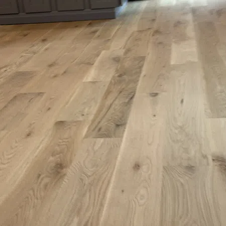 Natural light hardwood floor with varied wood grain patterns in a modern kitchen setting.