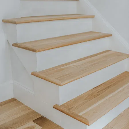 Close-up of wooden stairs with white risers and natural wood treads in a modern interior.