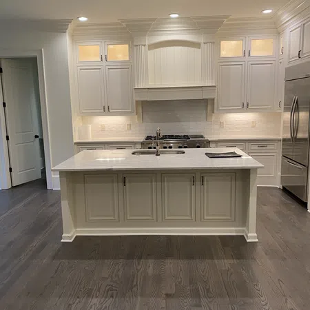 Modern kitchen with white cabinets, marble island, stainless steel appliances, and dark hardwood floors.
