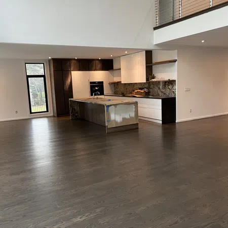 Spacious modern kitchen with dark hardwood floors, large island, white and wood cabinetry, and stainless steel appliances.