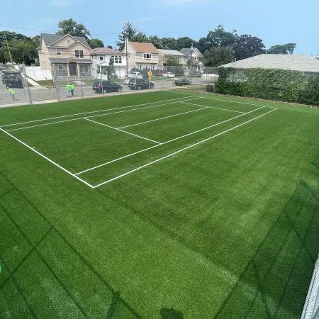 a green field with a fence and a building in the background