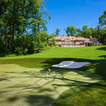 a golf course with a large house in the background