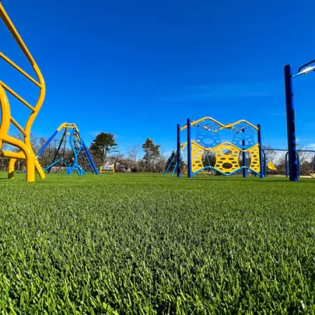 a grassy field with a playground set up in the background