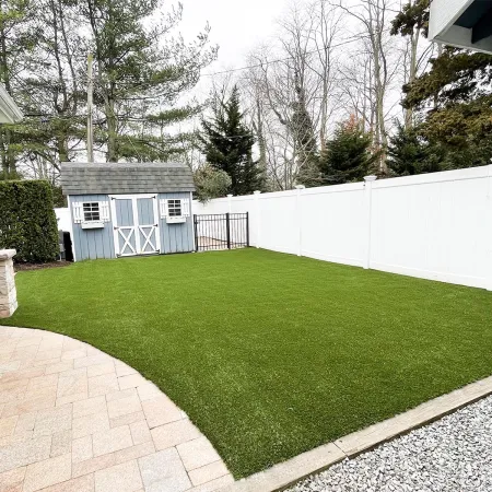 a fenced yard with a house and trees in the background