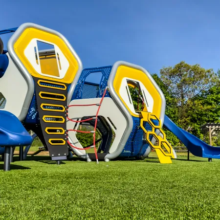 a yellow and blue playground slide with Disney's Pop Century Resort in the background