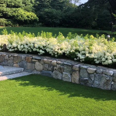 a stone wall with a stone fence and grass and trees