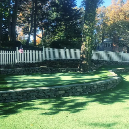 a stone wall with a fence and trees in the background