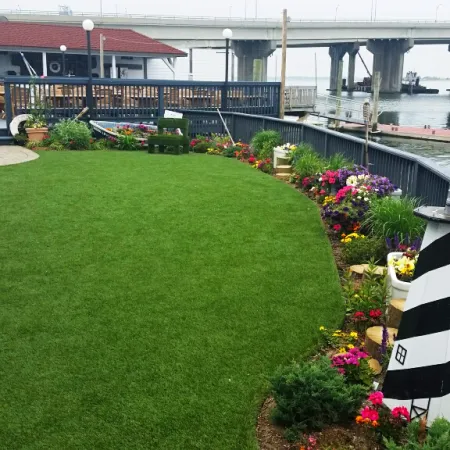 a lawn with chairs and tables by a body of water