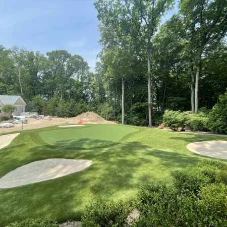 a golf course with trees and a house in the background