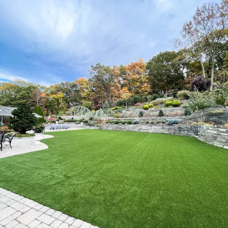 a large green lawn with a pond and trees in the background