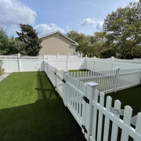 a white fence with a white picket fence and a house in the background