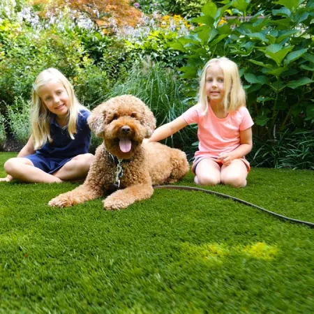 two girls sitting on grass with a dog
