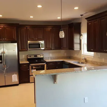 Modern kitchen with dark wood cabinets, stainless steel appliances, granite countertops, and pendant lighting.