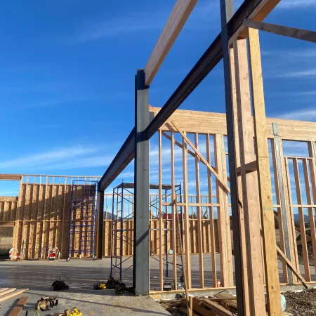 Framed wooden structure of a house under construction with clear blue sky background.