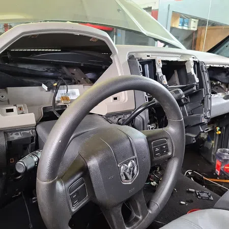 Interior of a disassembled Dodge vehicle dashboard with steering wheel and exposed wiring and components.