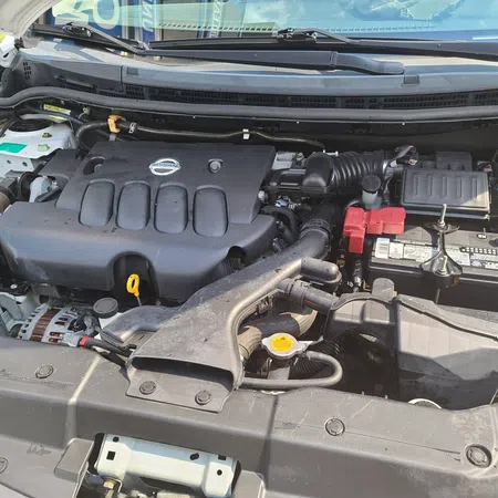 Clean Nissan car engine bay showing battery, air intake, and engine cover with Nissan logo