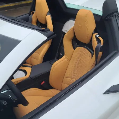 Close-up of tan leather sports car seats inside a white convertible with black interior accents.