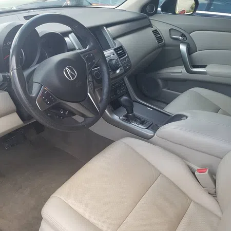 Spacious beige leather interior of Acura car with steering wheel, dashboard, and center console visible.