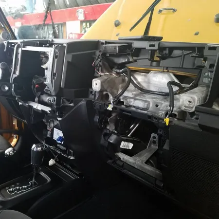 Car interior dashboard partially disassembled showing exposed wiring and components.