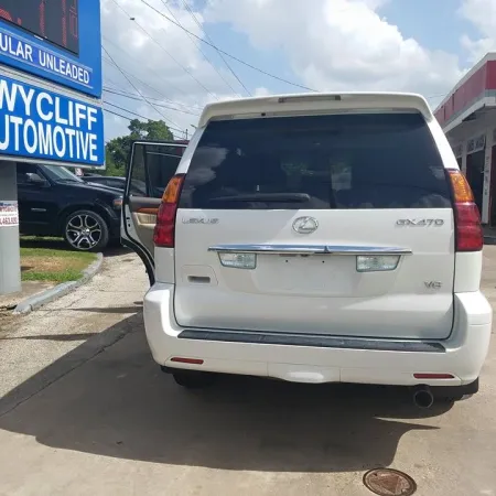White Lexus GX470 SUV parked at Wycliff Automotive shop with open door and visible signage.
