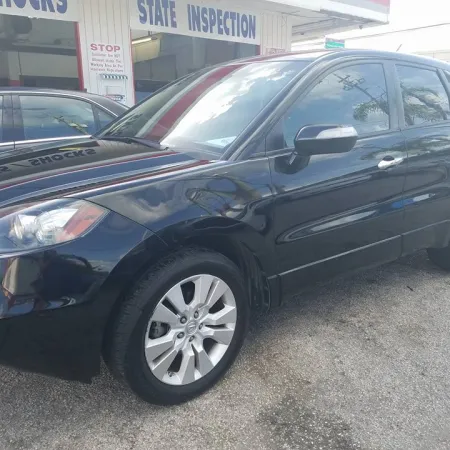 Black compact SUV parked outside a state inspection and auto service shop on a sunny day.
