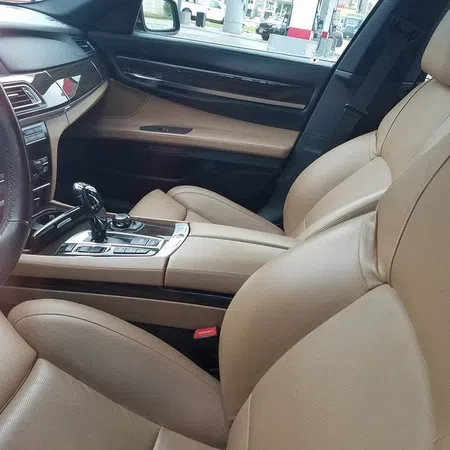 Luxury car interior with beige leather seats and modern center console controls.