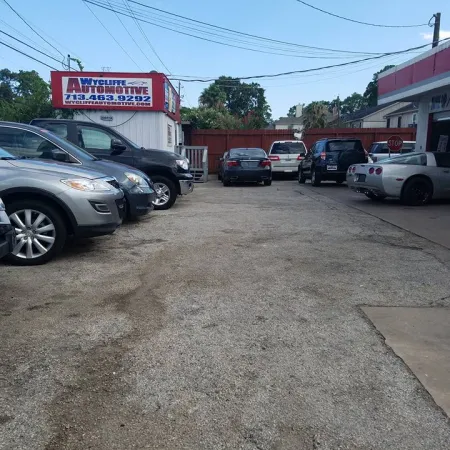 Parking lot with various cars outside Wycliffe Automotive repair shop on a sunny day.