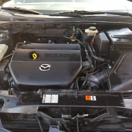 Open hood view of a Mazda car engine showcasing the clean engine cover and surrounding components.