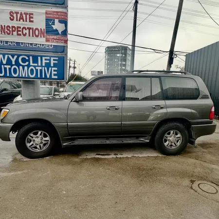 Gray SUV parked beside Wycliff Automotive signs and state inspection banners on a cloudy day.