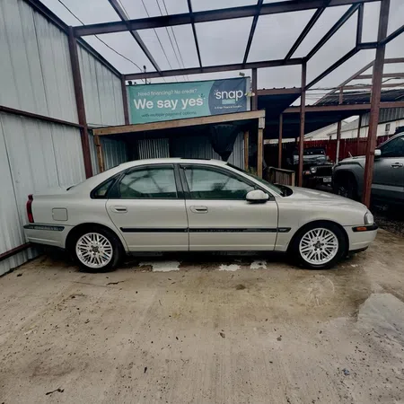 Silver sedan parked in a covered outdoor area with a financing sign in the background