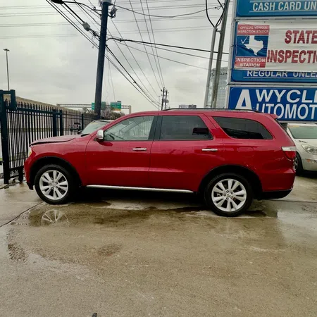 Red SUV parked on wet concrete near automotive inspection station signs on a cloudy day