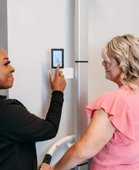 Two women interacting with a digital touchscreen panel on a modern refrigerator in a kitchen setting