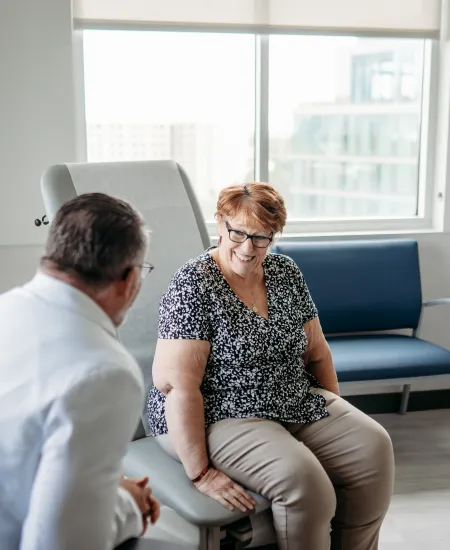 Senior woman smiling and talking with male doctor in a bright medical office during consultation.