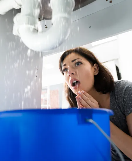a woman under the sink with a water leak
